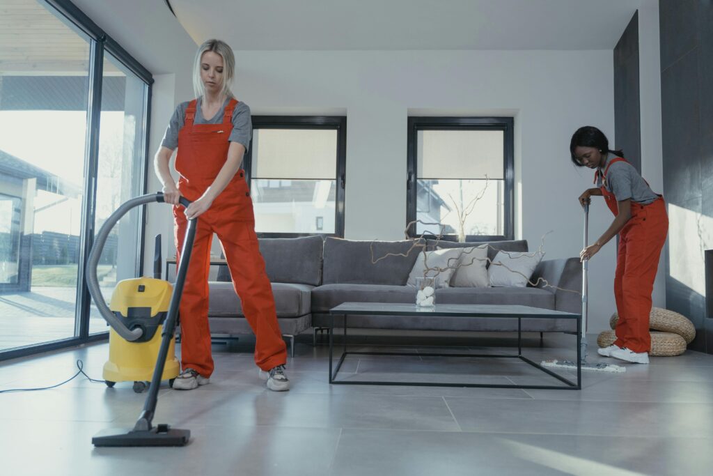 Two professional cleaners vacuuming and mopping a modern home interior